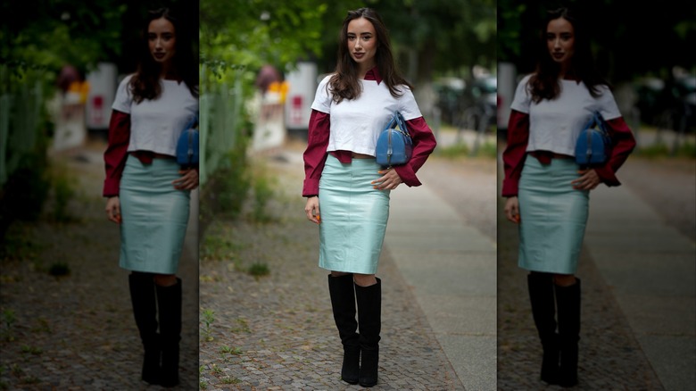 A woman wearing black suede boots and a blue pencil skirt.