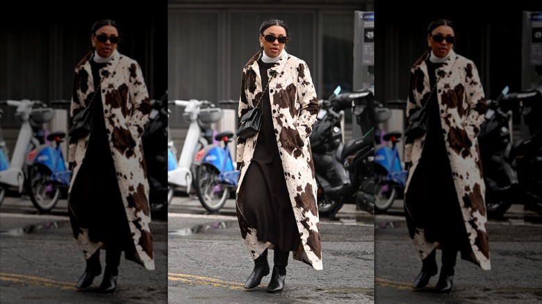 A woman wearing a brown and white full-length cow print coat.