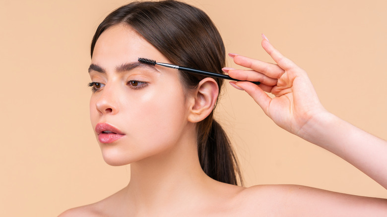 Woman brushing eyebrows with spoolie