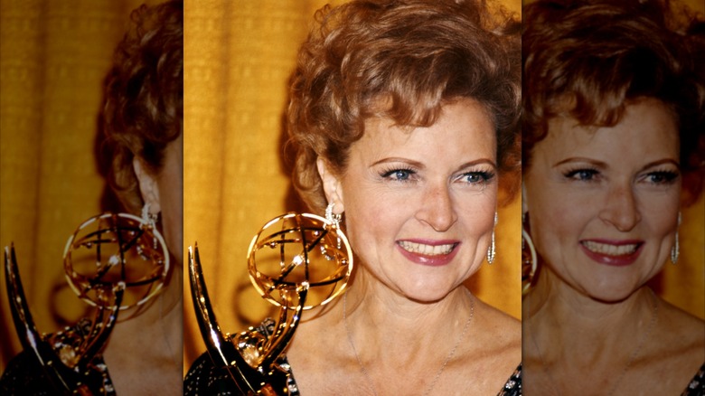 Betty White, US actress, smiling as she holds an Emmy Award, against a yellow background, USA, circa 1975