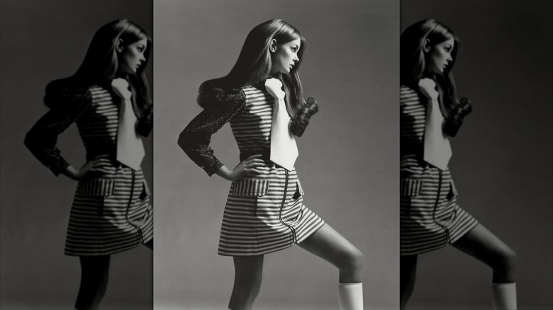 Jean Shrimpton poses wearing an oversized tie and a striped minidress