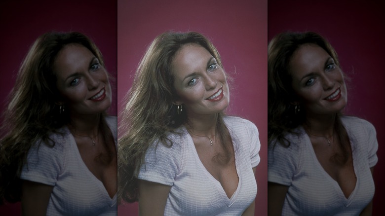 Catherine Bach poses wearing her hair down and a white T-shirt
