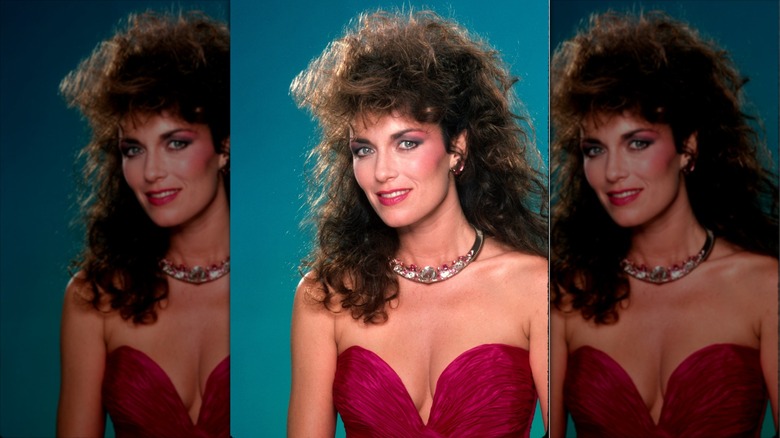 Catherine Bach smiles with a voluminous mullet wearing a crystal choker and a pink strapless top