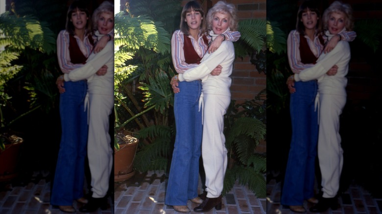 Jamie Lee Curtis wearing flared jeans, a striped shirt, and brown vest with Janet Leigh wearing a white outfit in 1979.