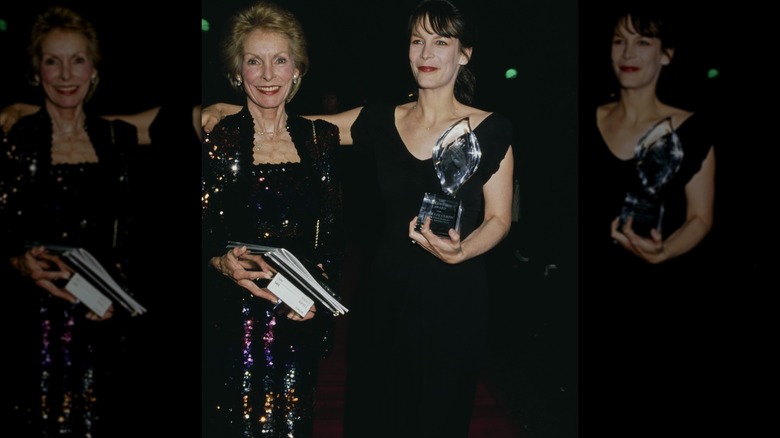Janet Leigh wearing a sparkly dress posing with Jamie Lee Curtis wearing a black dress holding a People's Choice Award in March 1990.