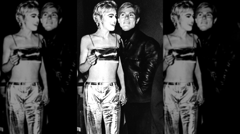 Edie Sedgwick wearing a two-piece silver lamé outfit standing with pop artist Andy Warhol at the Mod Ball.
