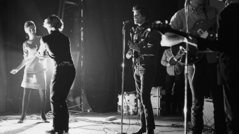 The Velvet Underground performing on stage with Edie Sedgwick and Gerard Malanga dancing.