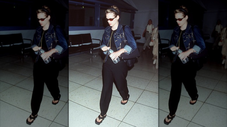 Winona Ryder photographed at the airport in black pants, a denim jacket, and sunglasses.