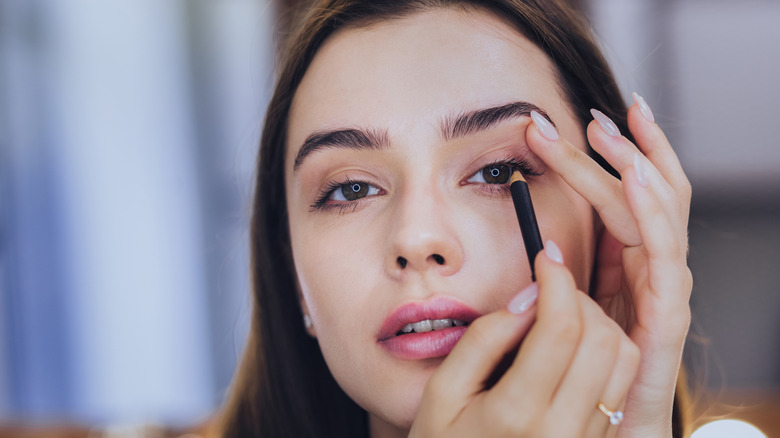 Woman applying black eyeliner