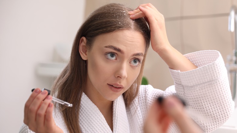 Person with dandruff applying serum to scalp