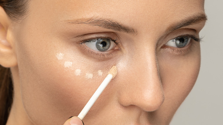 Woman applying dots of concealer