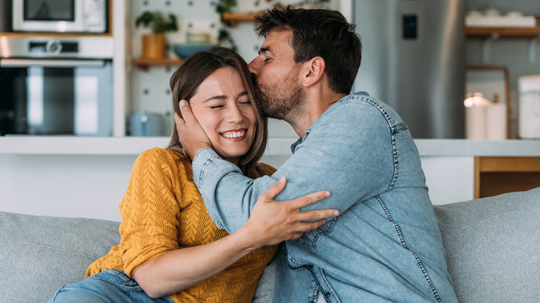 man kissing woman on sofa