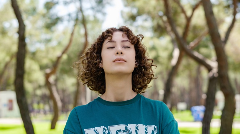 woman closing her eyes in the park