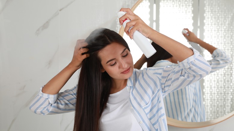 Woman styling hair with hairspray 