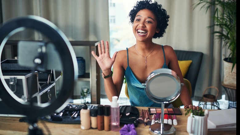 Woman surrounded by table of makeup