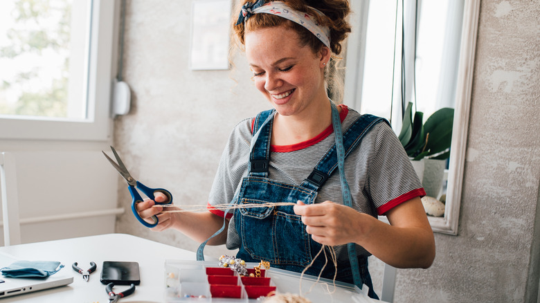 Smiling woman making jewelry at home