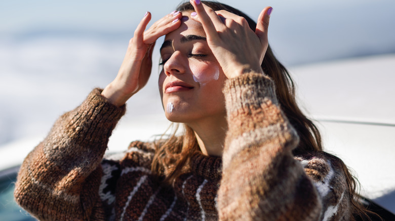 Woman applying skin cream in wintry setting