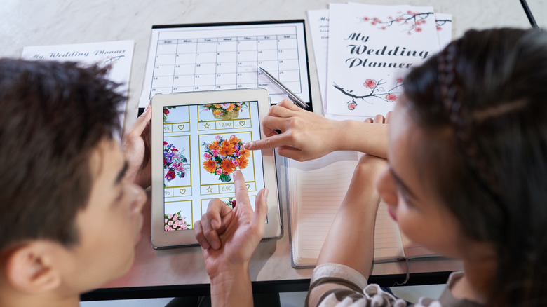 Couple choosing wedding flowers on tablet