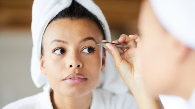 Woman tweezing her eyebrows