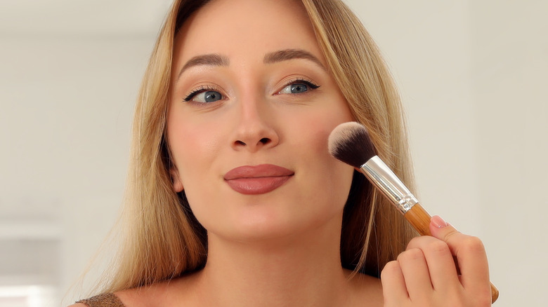 woman applying makeup to face