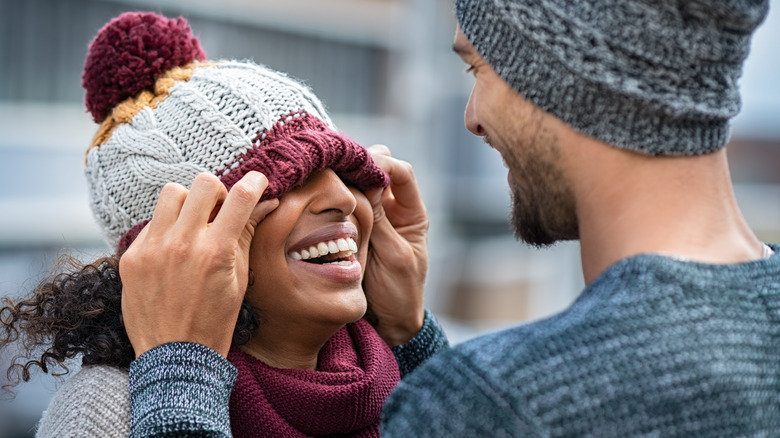 Boyfriend playfully pulling on girlfriend's winter hat