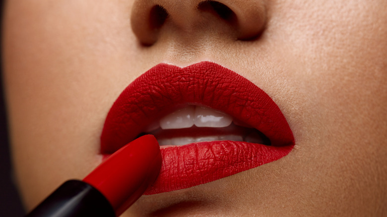 applying matte red lipstick