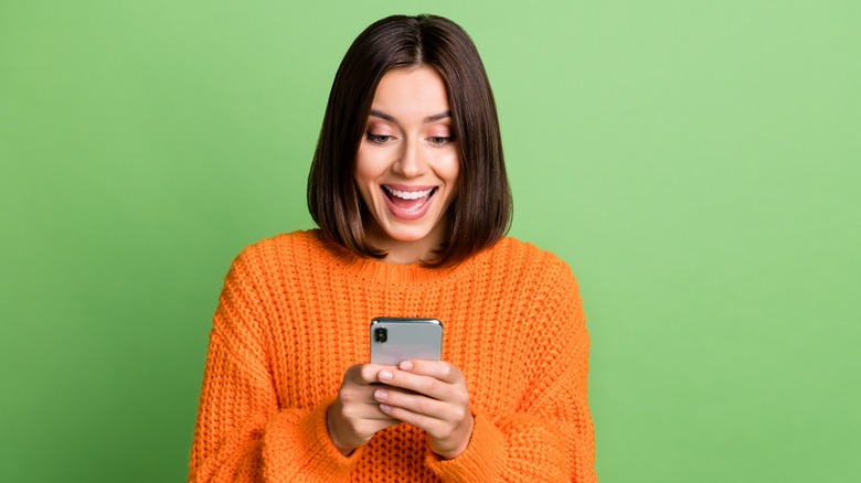 Woman in orange sweater texting 