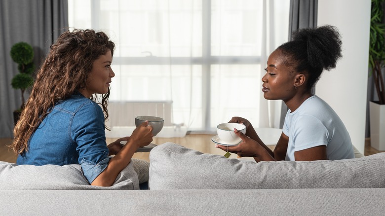 Women have discussion over coffee on sofa