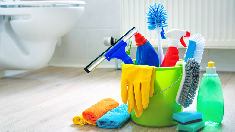 cleaning supplies in green bucket on bathroom floor