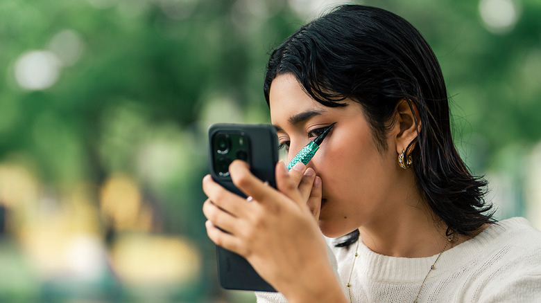 A woman applying eyeliner