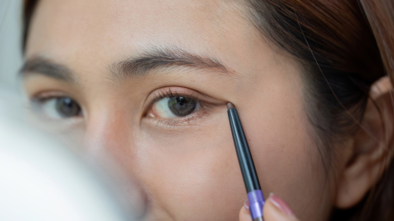 Closeup of woman applying subtle eyeliner