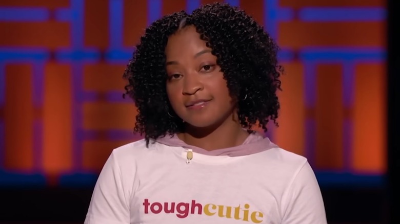 ToughCutie founder Brittany Coleman wears a white t-shirt with her company logo over a long-sleeve pink hooded shirt while pitching her business on Shark Tank, airing in January 2025.