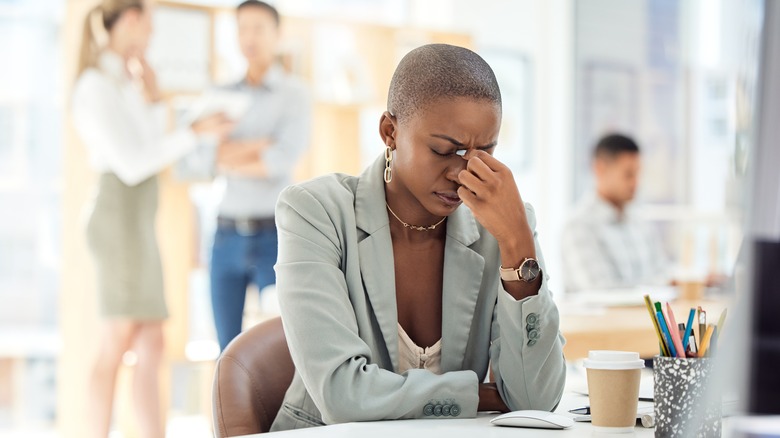 Stressed businesswoman pinches bridge of nose