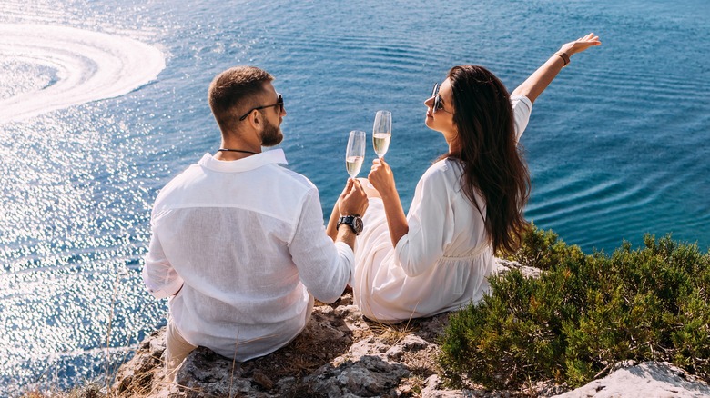 Couple toasting champagne on sea cliff