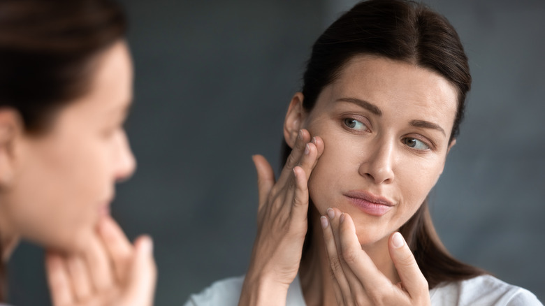 woman looking at her facial skin