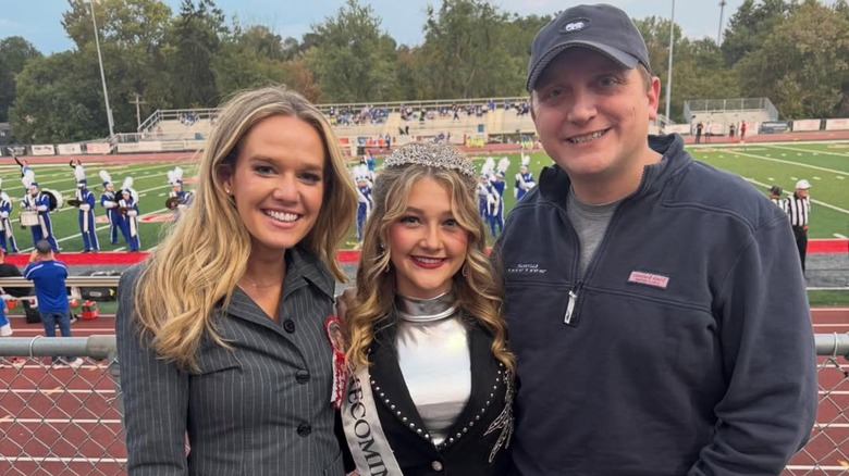 Tricia McLaughlin and fiance flank high schooler during homecoming game