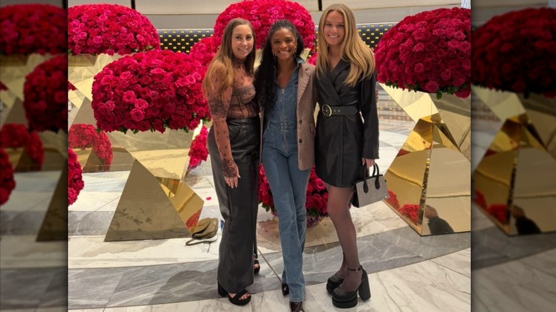 Tricia McLaughlin, right, poses with two women in front of giant bunches of flowers