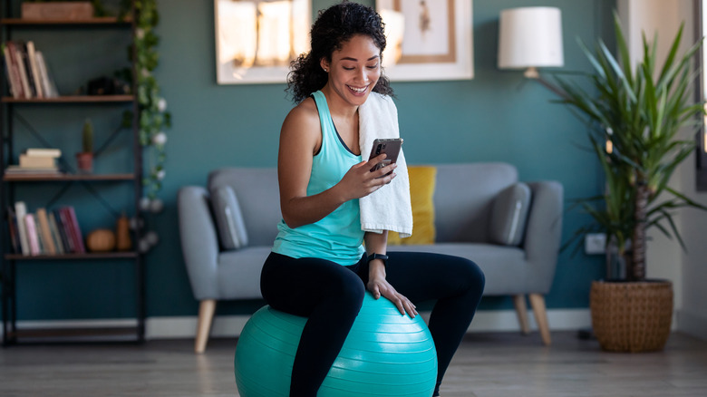Woman on yoga ball smiling at phone