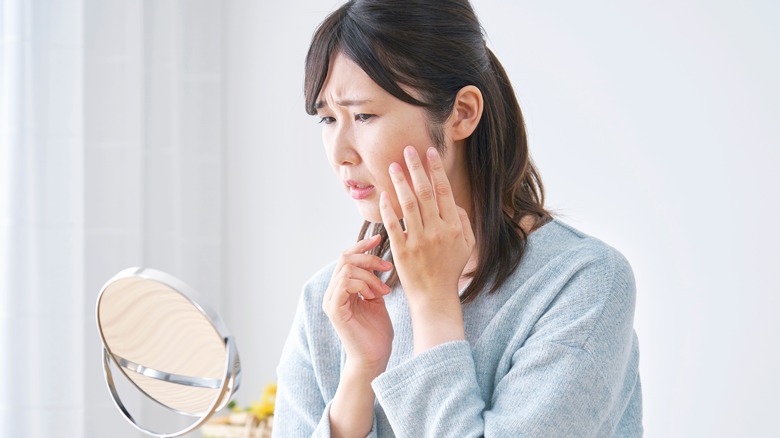 Woman looking at skin in mirror