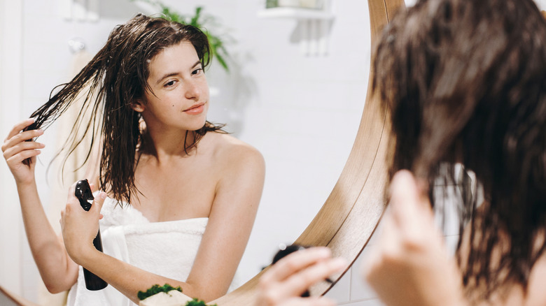 Woman spraying hair with bottle