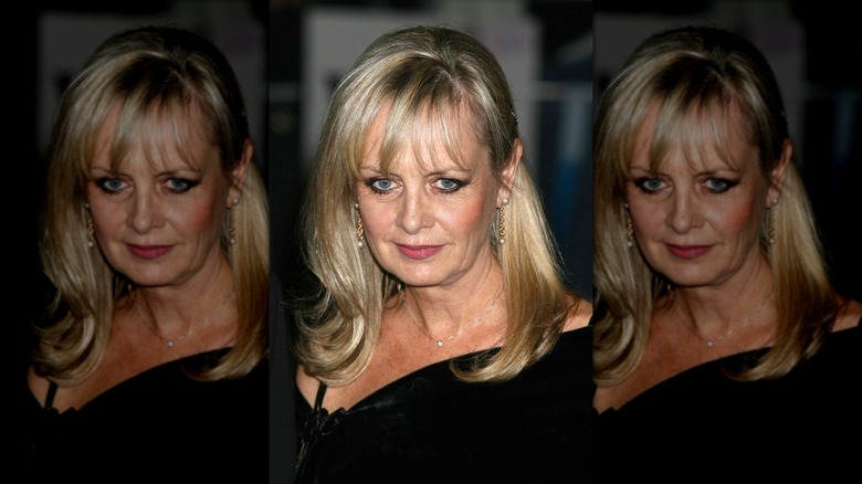 Twiggy looks down wearing a black top and black eyeliner