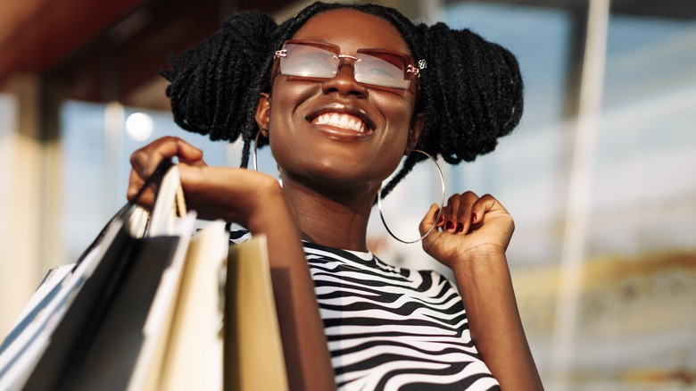 Woman smiling while holding several shopping bags