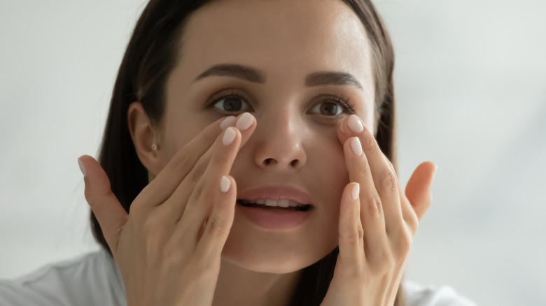 woman touching under her eyes 