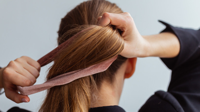 Woman tying hair with a scrunchie