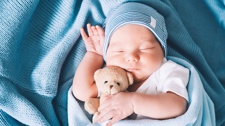 A baby boy sleeping peacefully while holding a stuffie