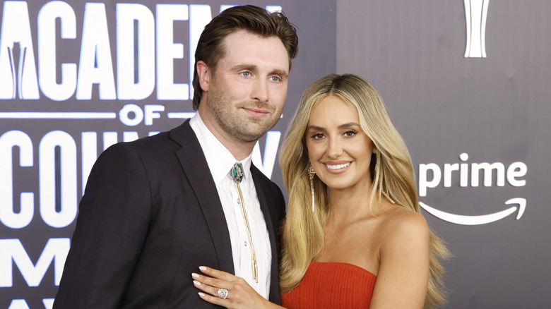 Lainey Wilson poses with husband Devlin Hodges in a red strapless evening gown at the 61st Academy of Country Music Awards in Las Vegas in May 2026.