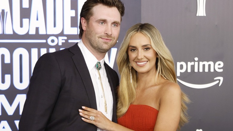 Lainey Wilson poses with husband Devlin Hodges in a red strapless evening gown at the 61st Academy of Country Music Awards in Las Vegas in May 2026.