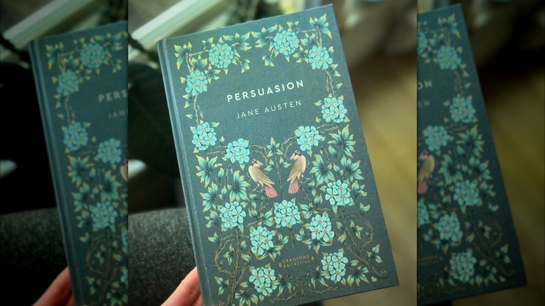 A hand holding up a copy of Jane Austen's 'Persuasion