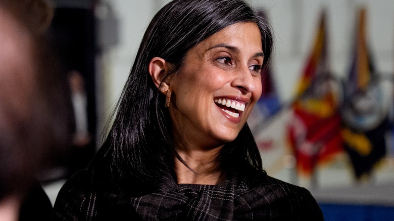 Close-up of Usha Vance. She is a middle-aged woman with brown skin and dark hair. In this image, she is smiling at someone off camera.