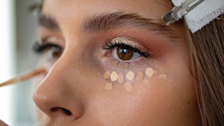 Woman applying concealer under her eyes